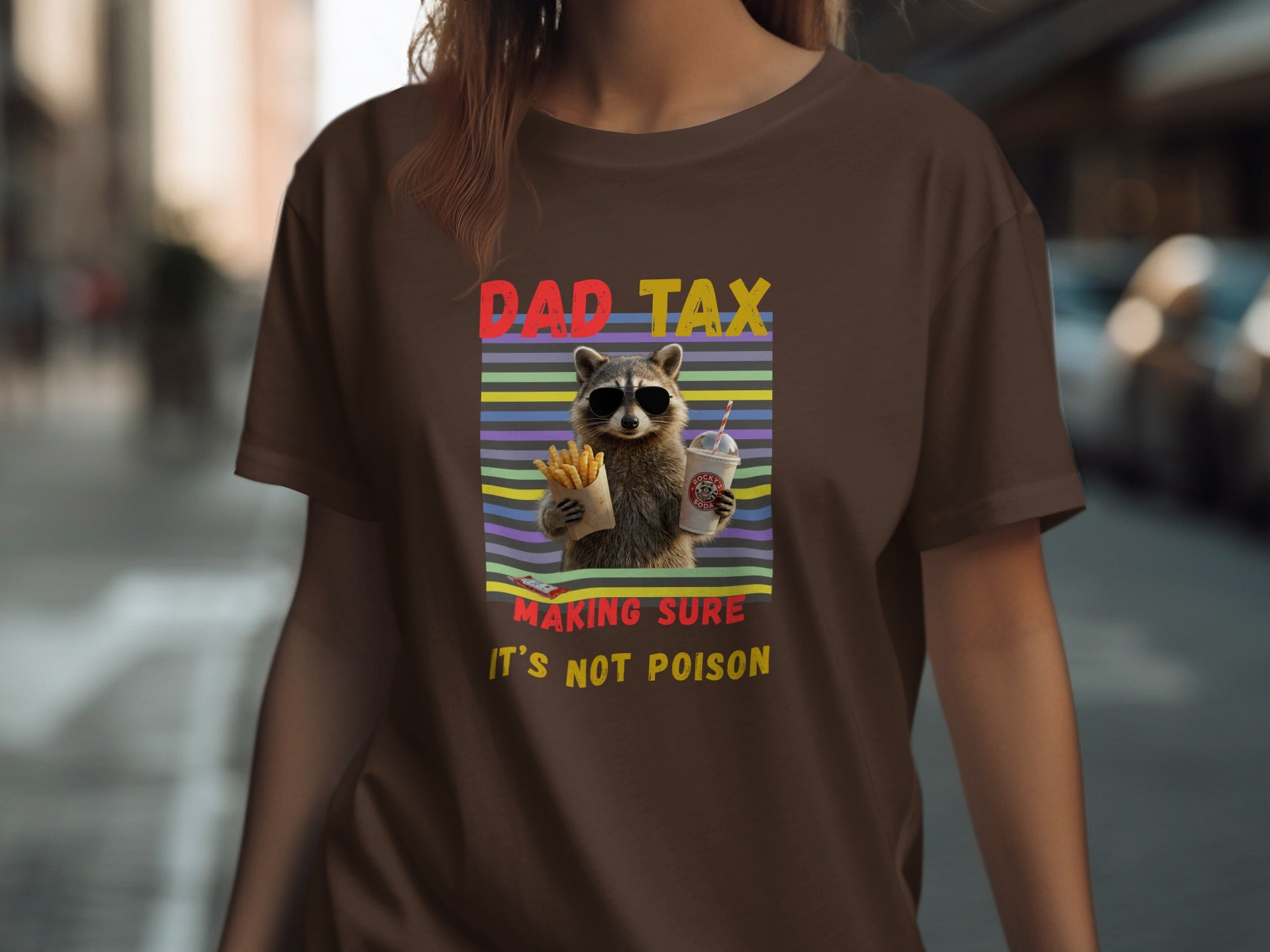 Brown t-shirt with raccoon graphic and text "DAD TAX MAKING SURE IT'S NOT POISON".