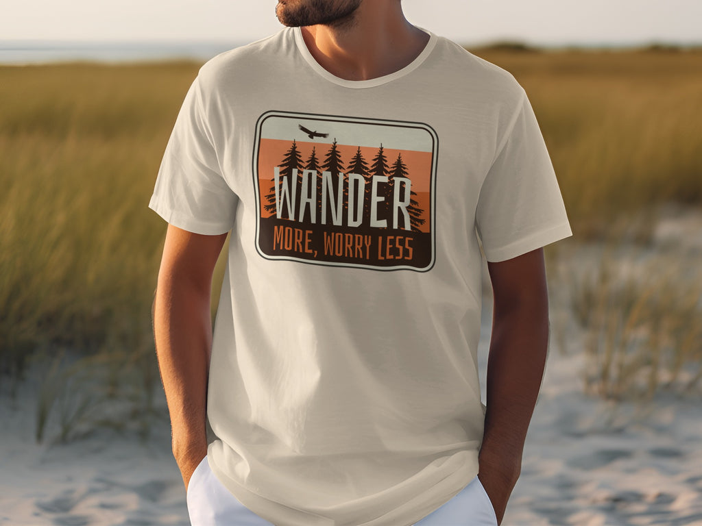 Cream t-shirt featuring a graphic with text "WANDER MORE, WORRY LESS" and pine trees.