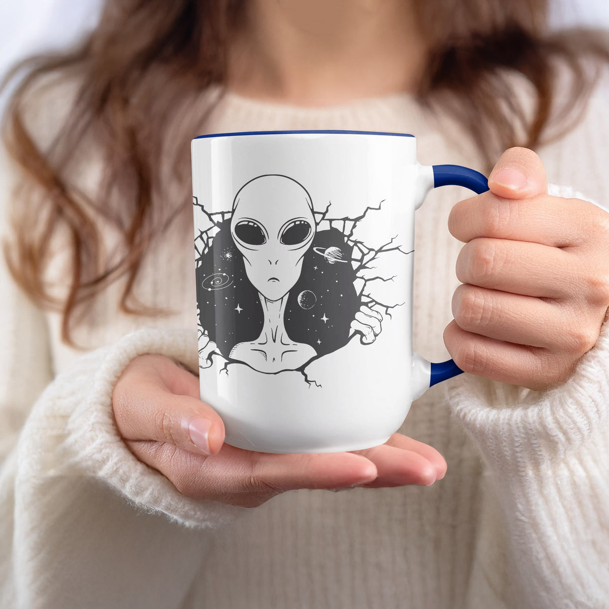White mug with blue rim featuring an alien face breaking through a starry background.