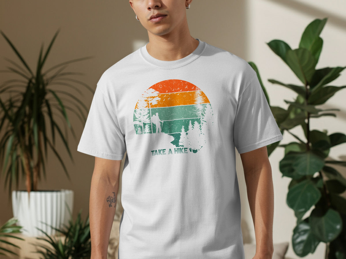 White t-shirt with distressed graphic of hikers and trees under a sunset with text "TAKE A HIKE".