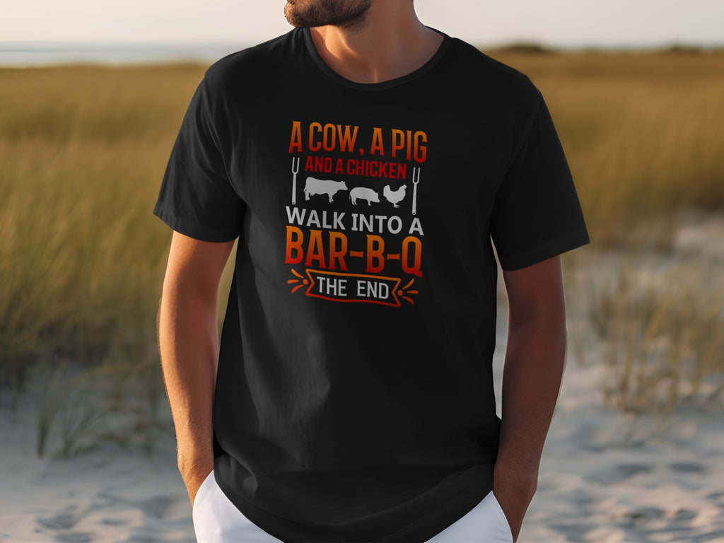 Black t-shirt with text: A cow, a pig and a chicken walk into a bar-b-q the end.