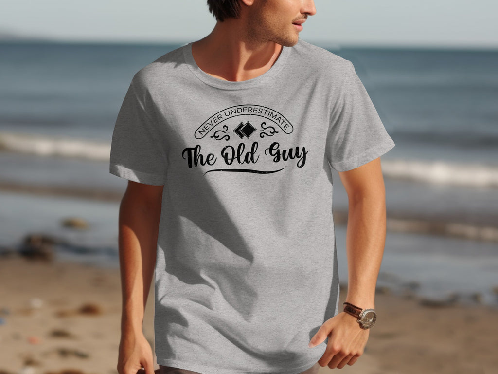 Grey t-shirt with black text: "NEVER UNDERESTIMATE The Old Guy".