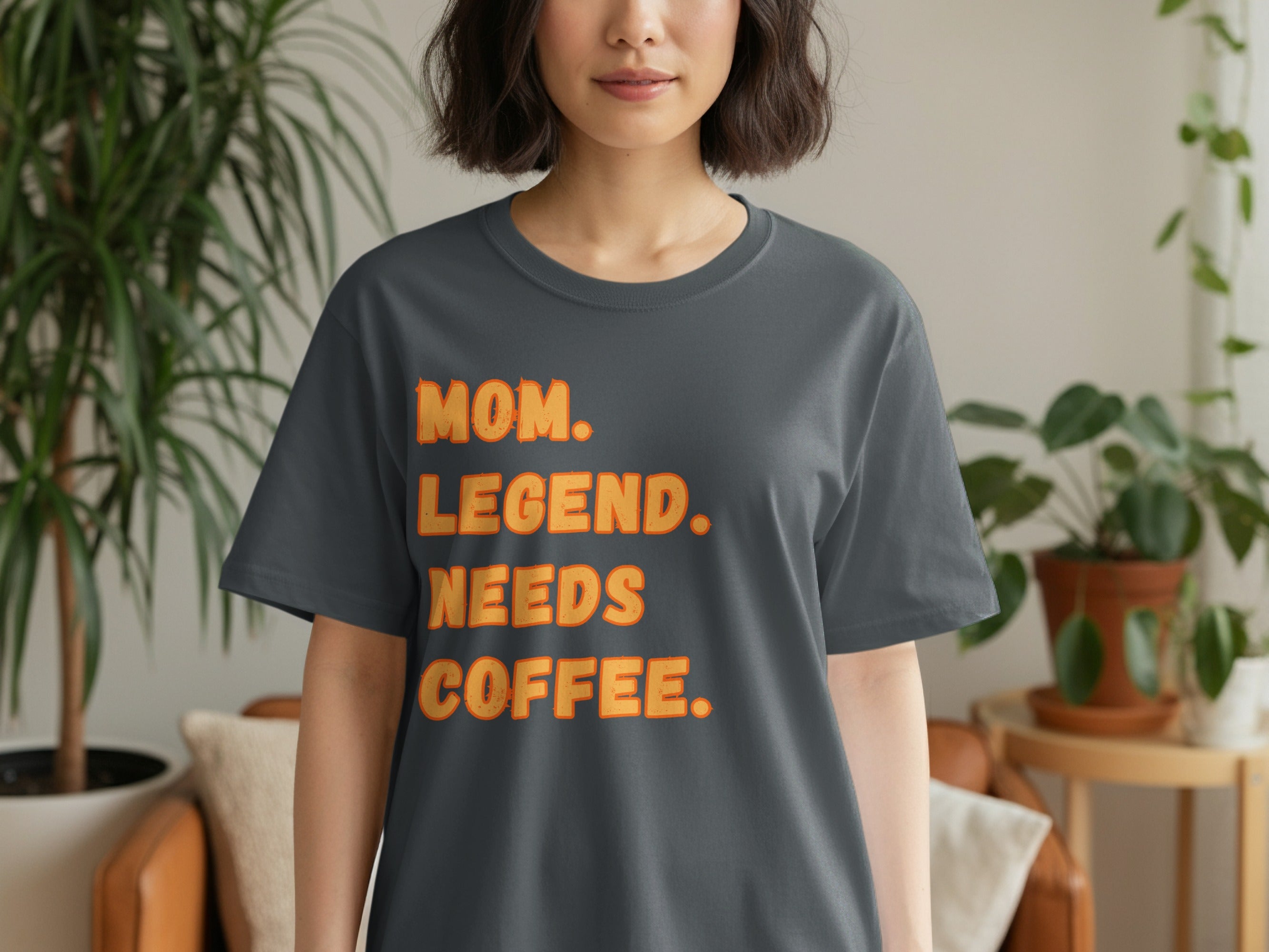 Dark gray t-shirt with orange text that reads "MOM. LEGEND. NEEDS. COFFEE."