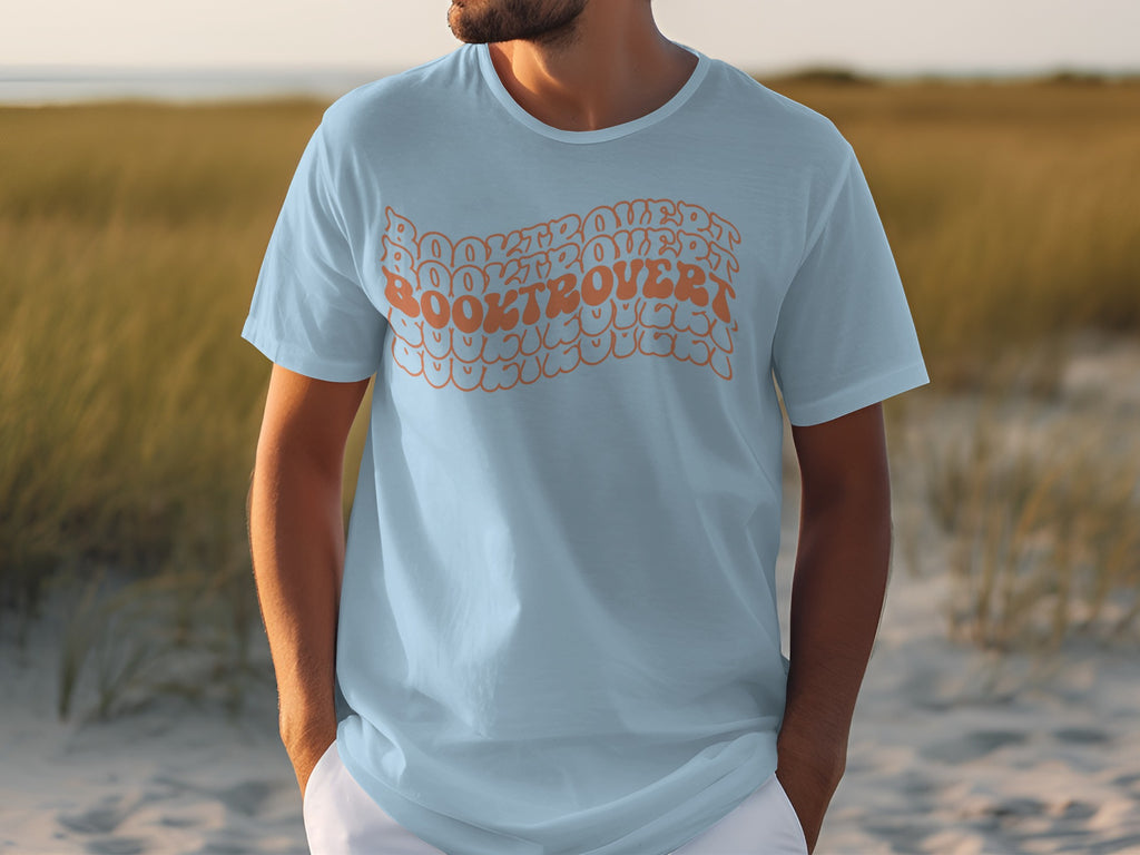 Light blue t-shirt with orange wavy text reading "BOOKTROVERT BOOKTROVERT BOOKTROVERT".