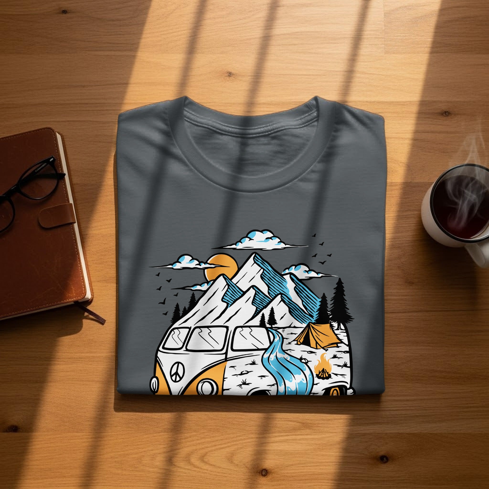 T-shirt graphic features a vintage van, mountains, tent, and campfire in a nature scene.