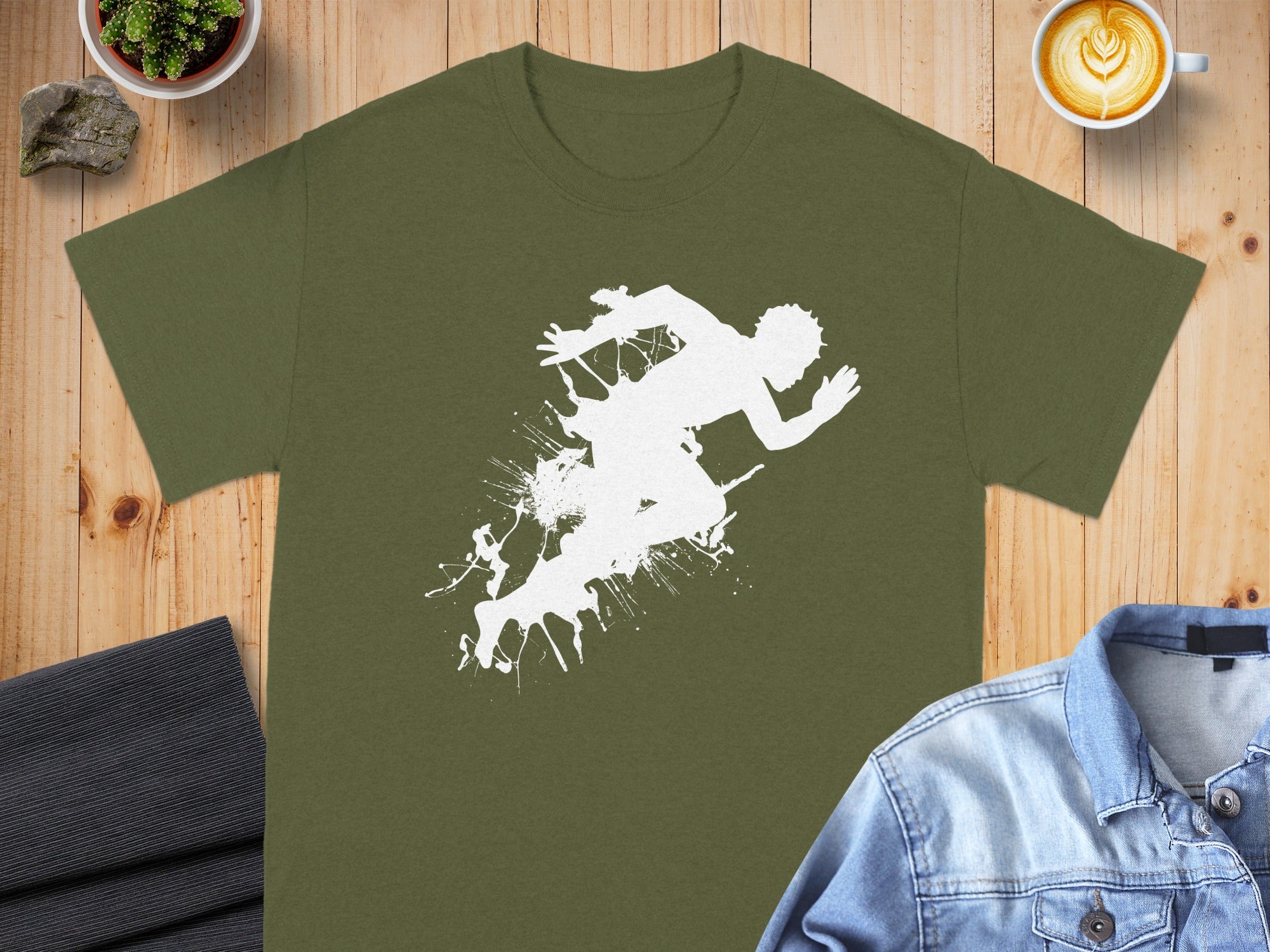 Green t-shirt with white splatter graphic of a running figure.