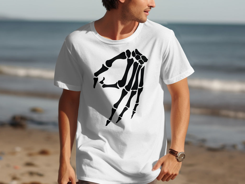 Man wearing white t-shirt with black skeleton hand graphic at beach