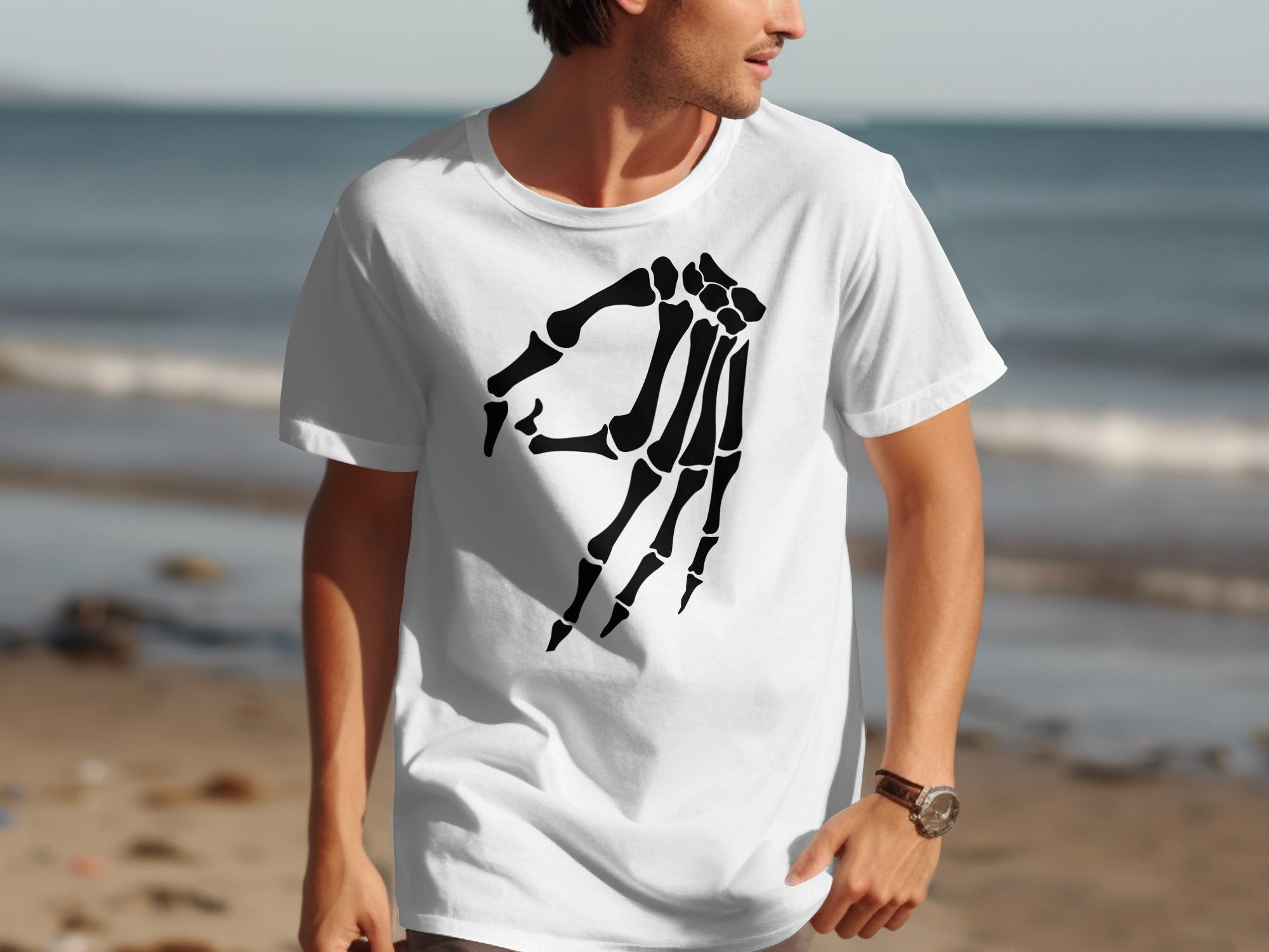 Man wearing white t-shirt with black skeleton hand graphic at beach