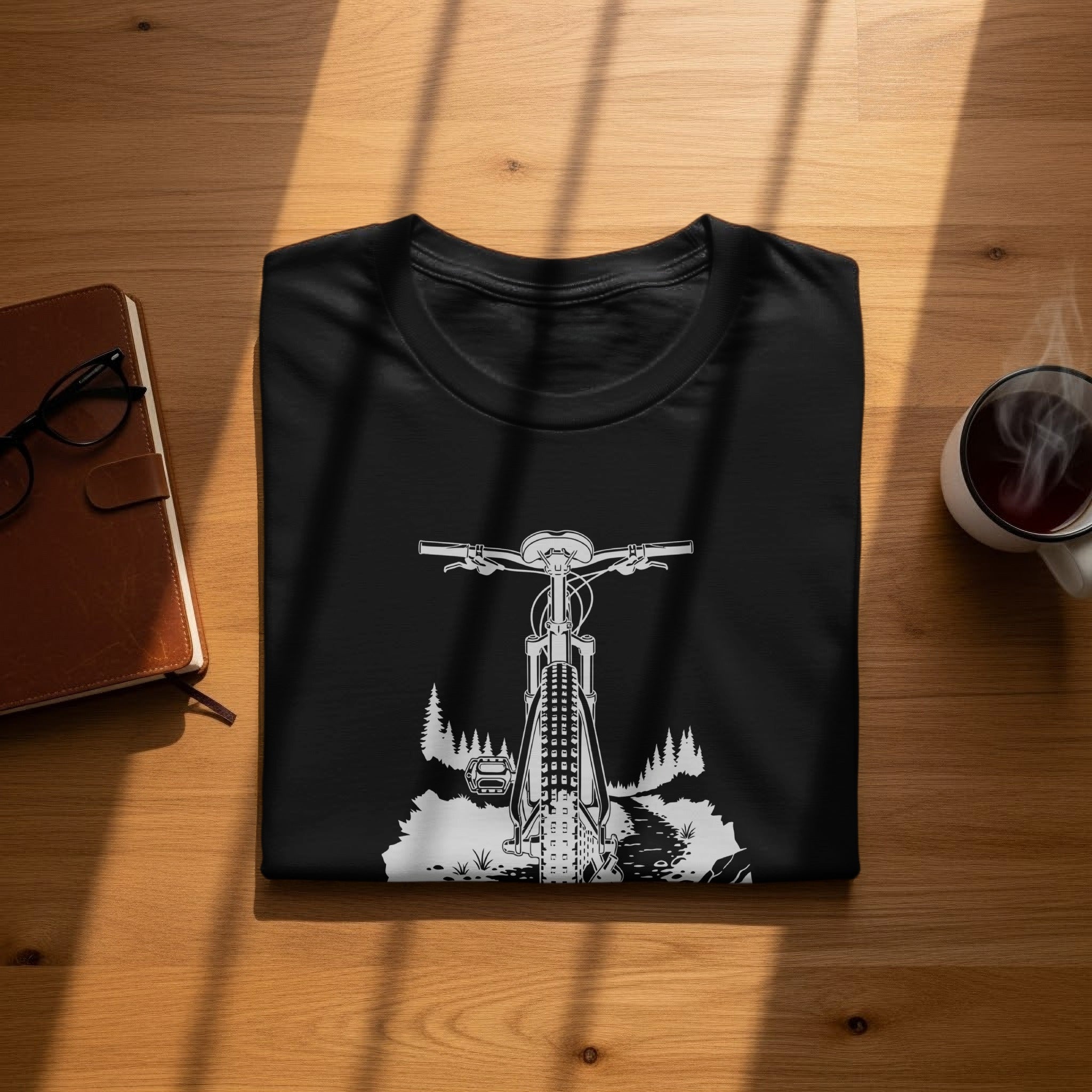 Black t-shirt with white graphic of bicycle on a wooded trail.