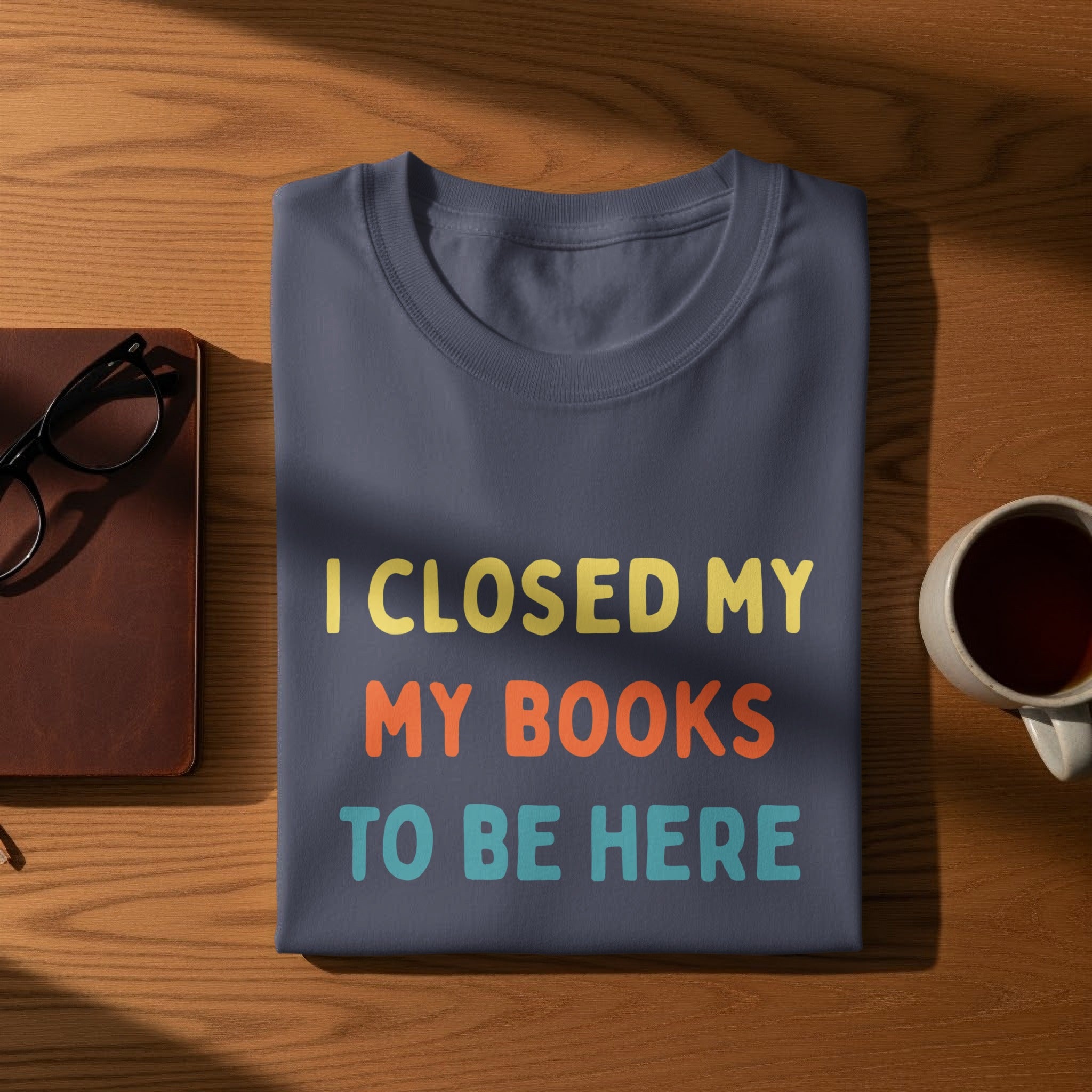T-shirt with text "I CLOSED MY MY BOOKS TO BE HERE" in colorful letters.