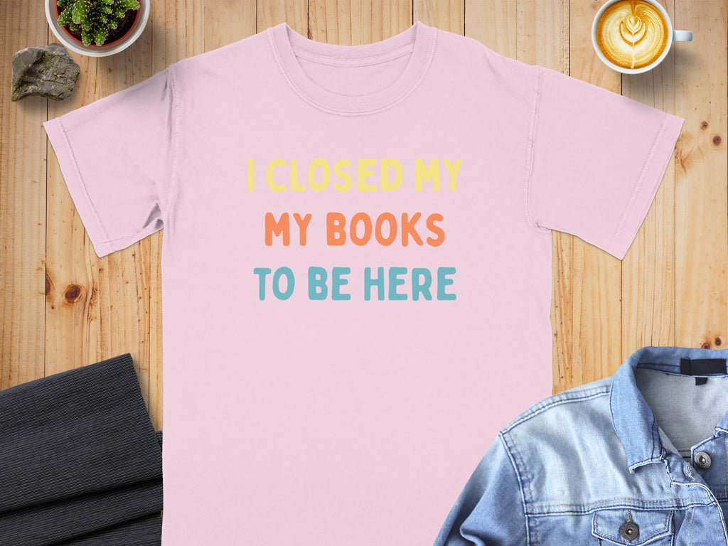Pink t-shirt with "I CLOSED MY MY BOOKS TO BE HERE" text in yellow, orange, and blue.