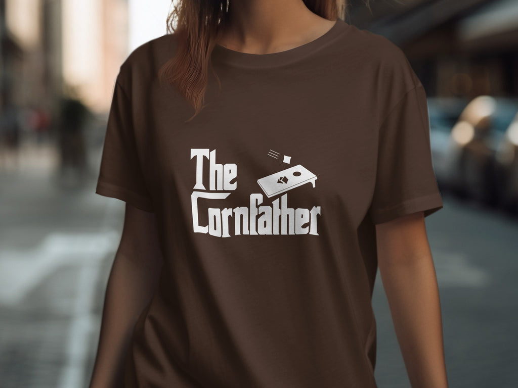 Brown t-shirt with white text and cornhole graphic reading "The Cornfather".
