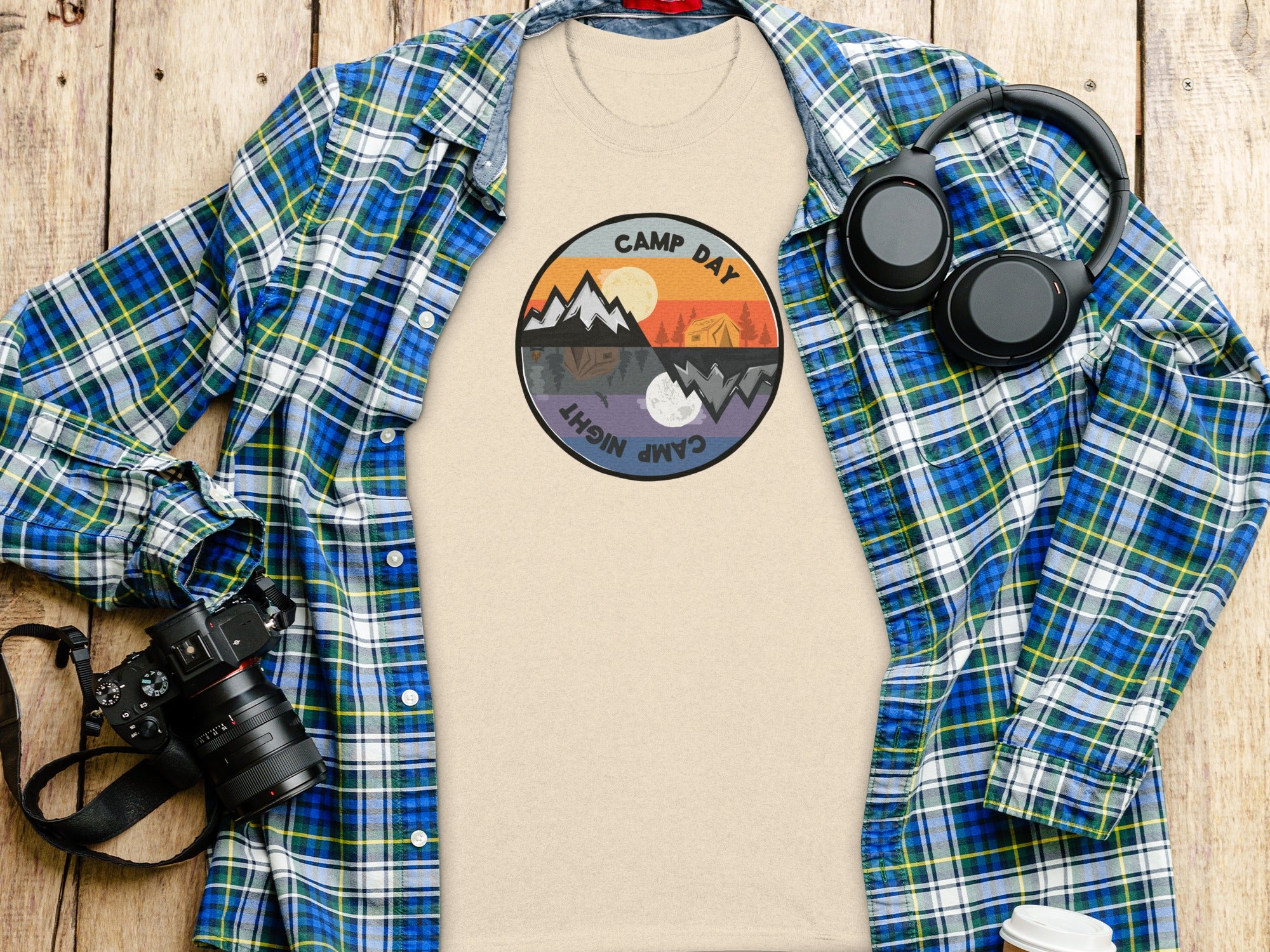 Beige t-shirt with a circular "Camp Day Night" graphic, unfolded blue plaid shirt.