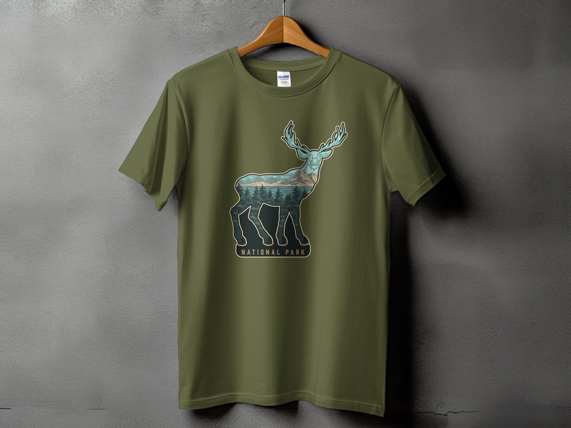 Olive green t-shirt with a deer silhouette filled with a forest and mountains scene.