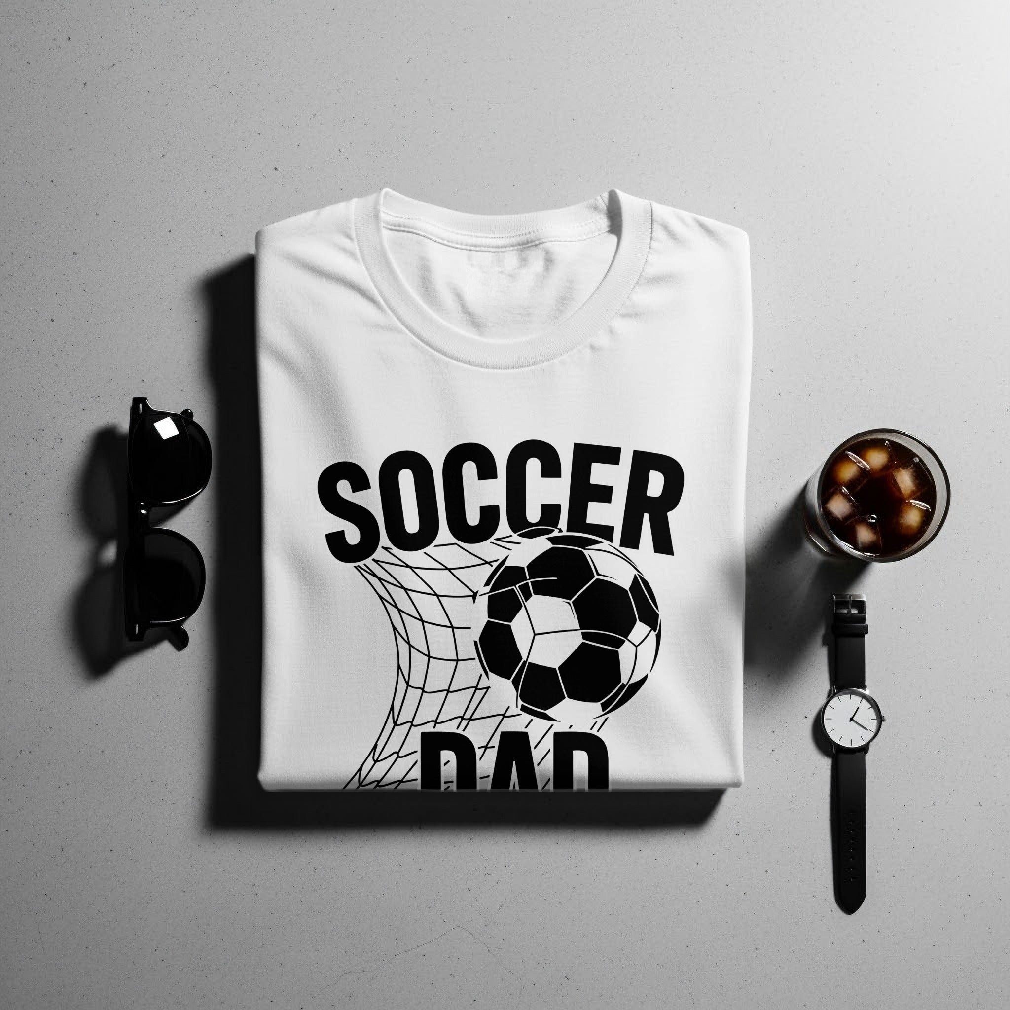 White t-shirt with black "SOCCER DAD" text and soccer ball in net graphic.