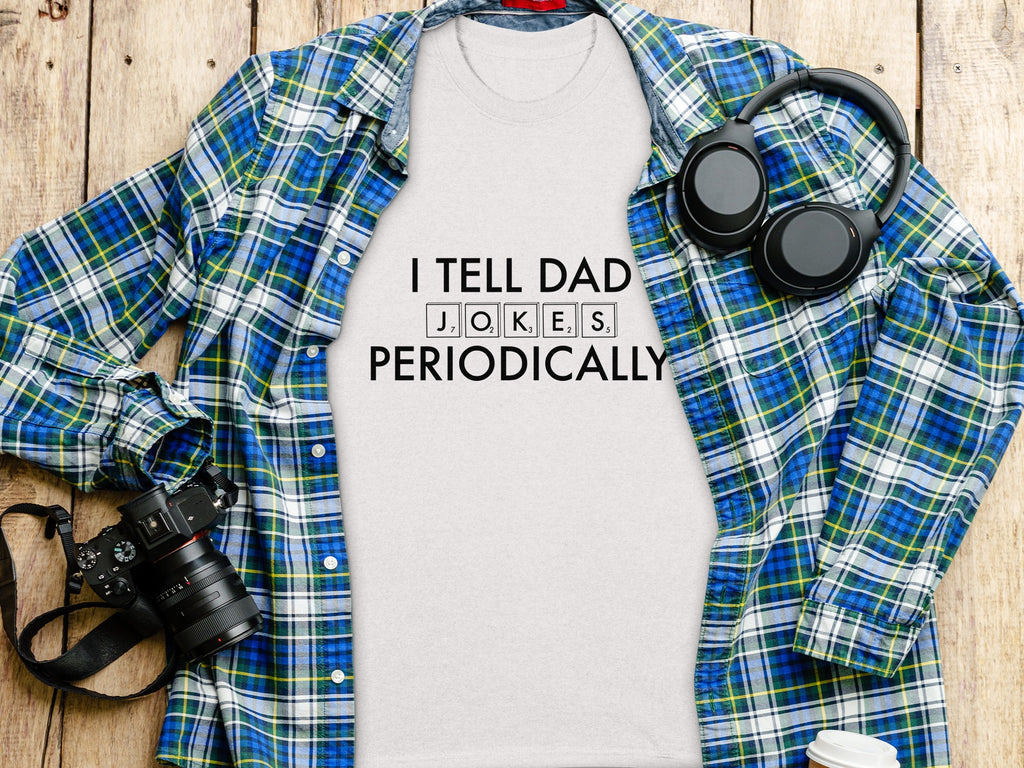 White t-shirt with "I TELL DAD JOKES PERIODICALLY" text, plaid shirt, headphones and camera.