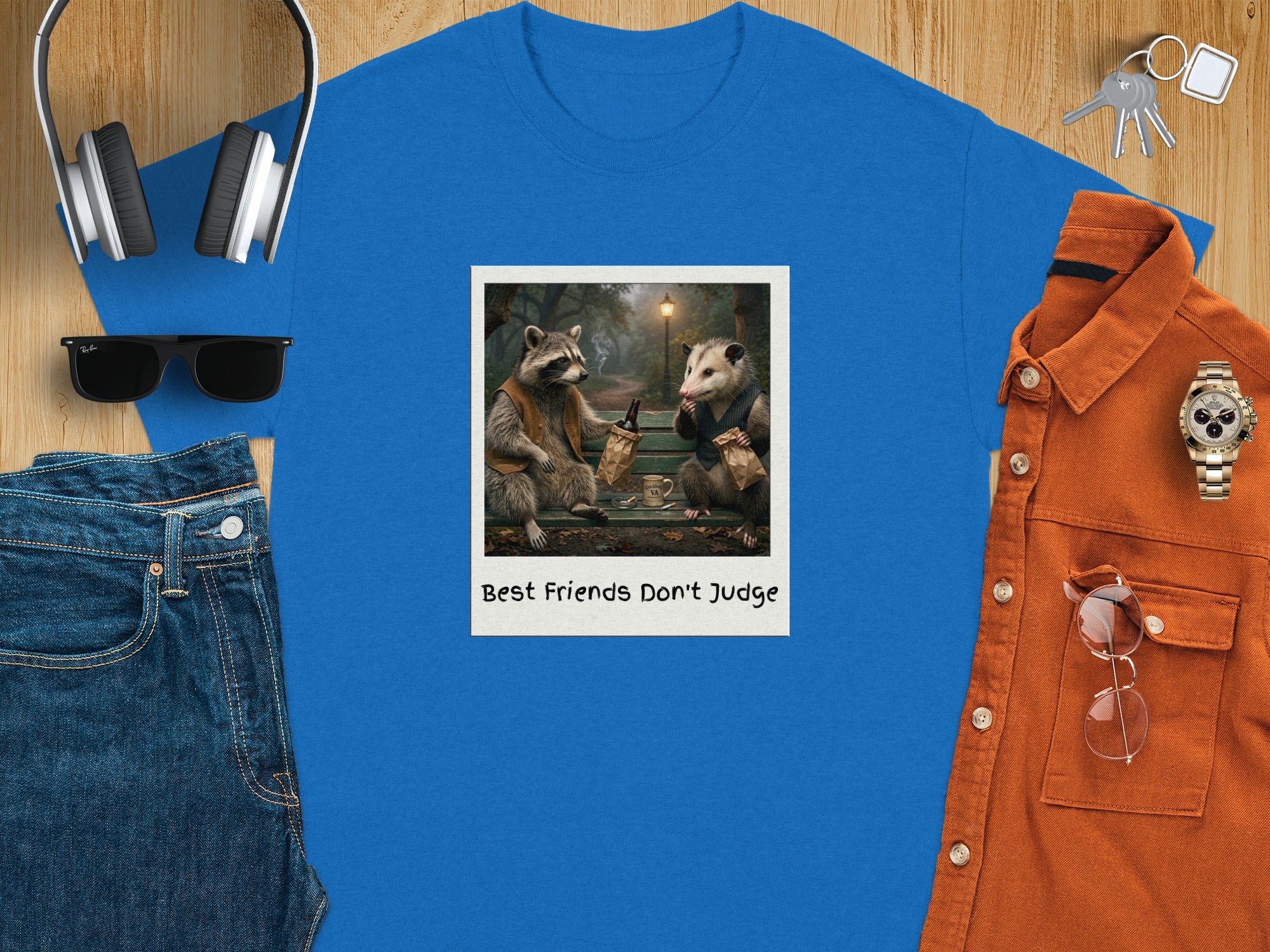 Blue t-shirt with polaroid print of raccoon and possum titled "Best Friends Don't Judge."