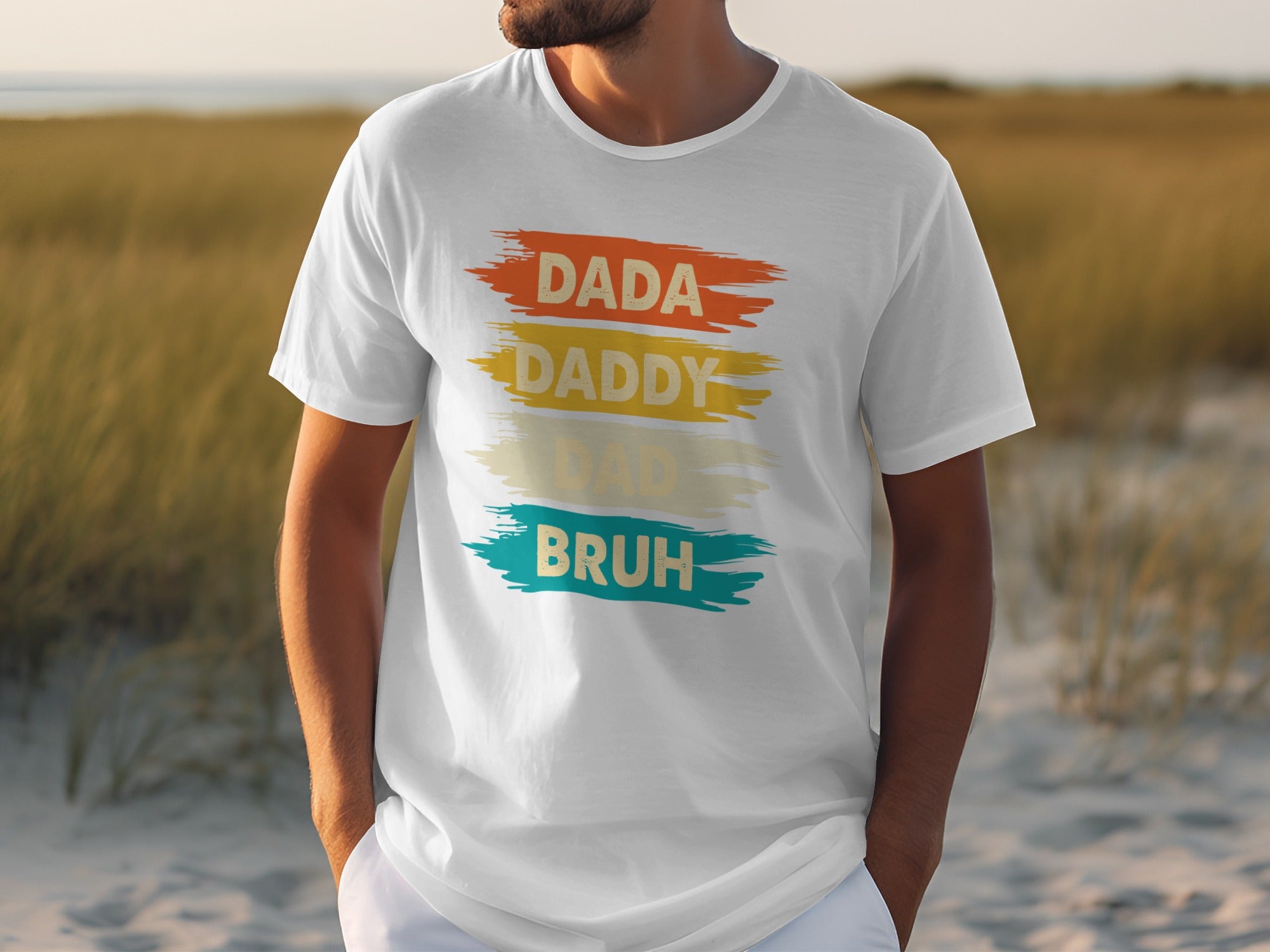 White t-shirt with "DADA DADDY DAD BRUH" text in colorful brush strokes.