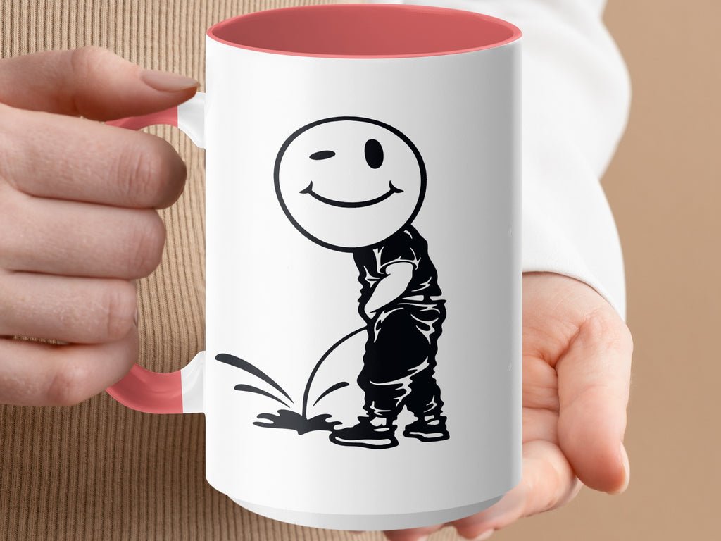 White mug with pink handle, featuring a cartoon figure with a winking smiley face urinating.