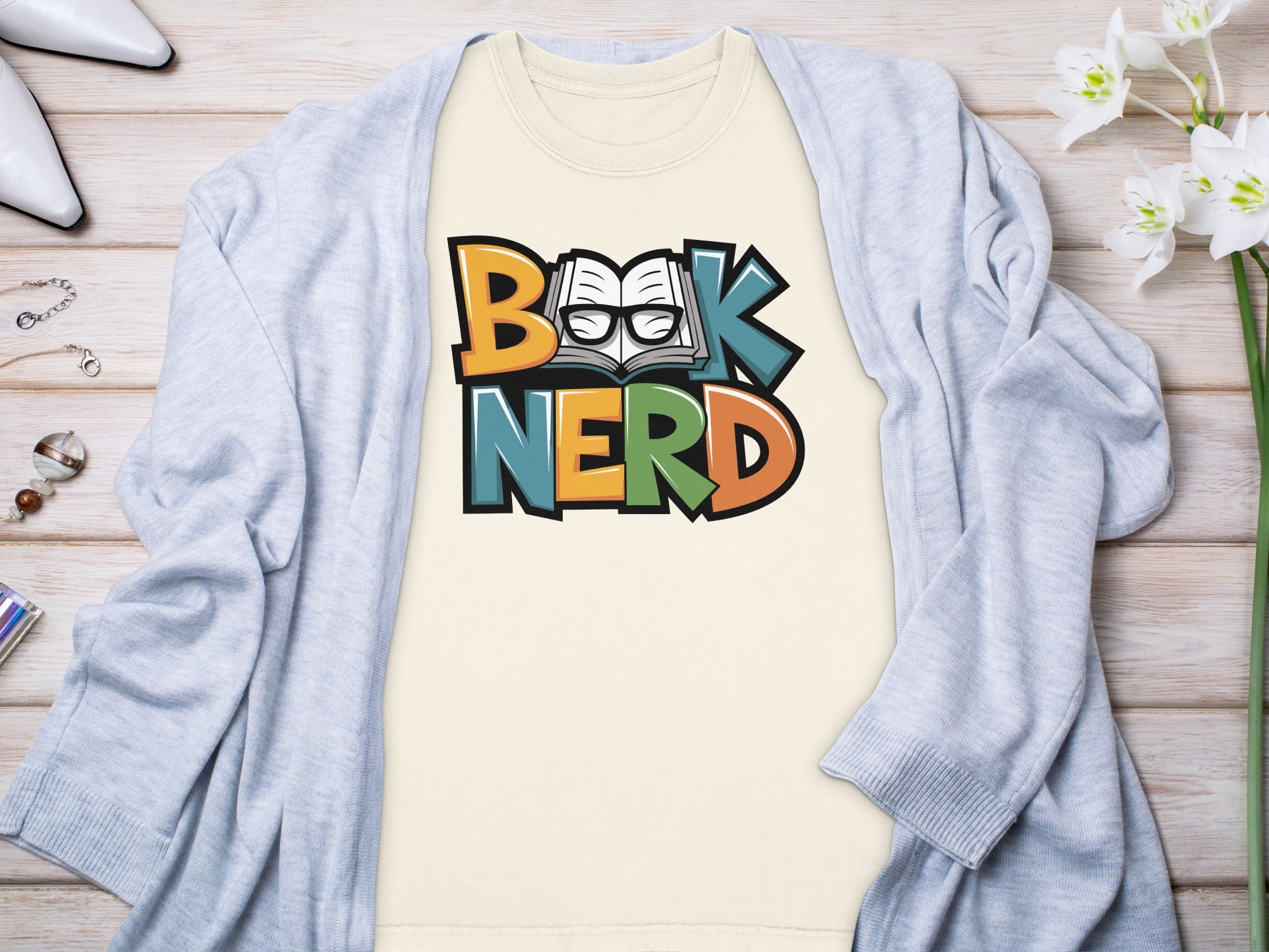 Cream t-shirt with colorful "Book Nerd" text and graphic of open book with glasses.