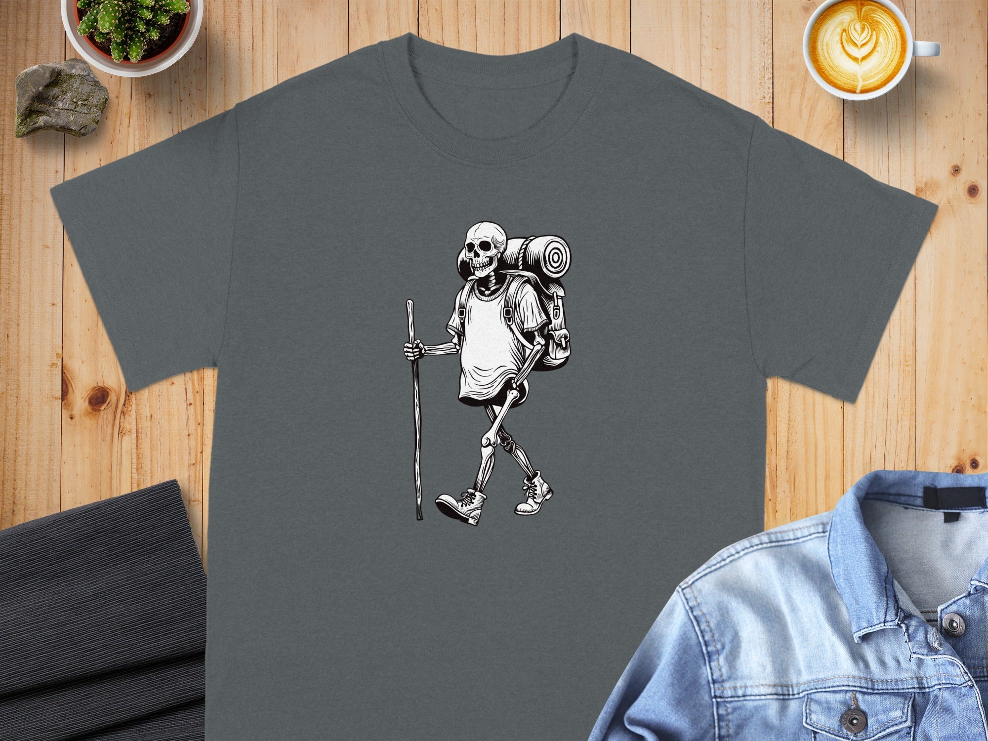 Skeleton hiker with backpack and walking stick graphic on charcoal t-shirt.
