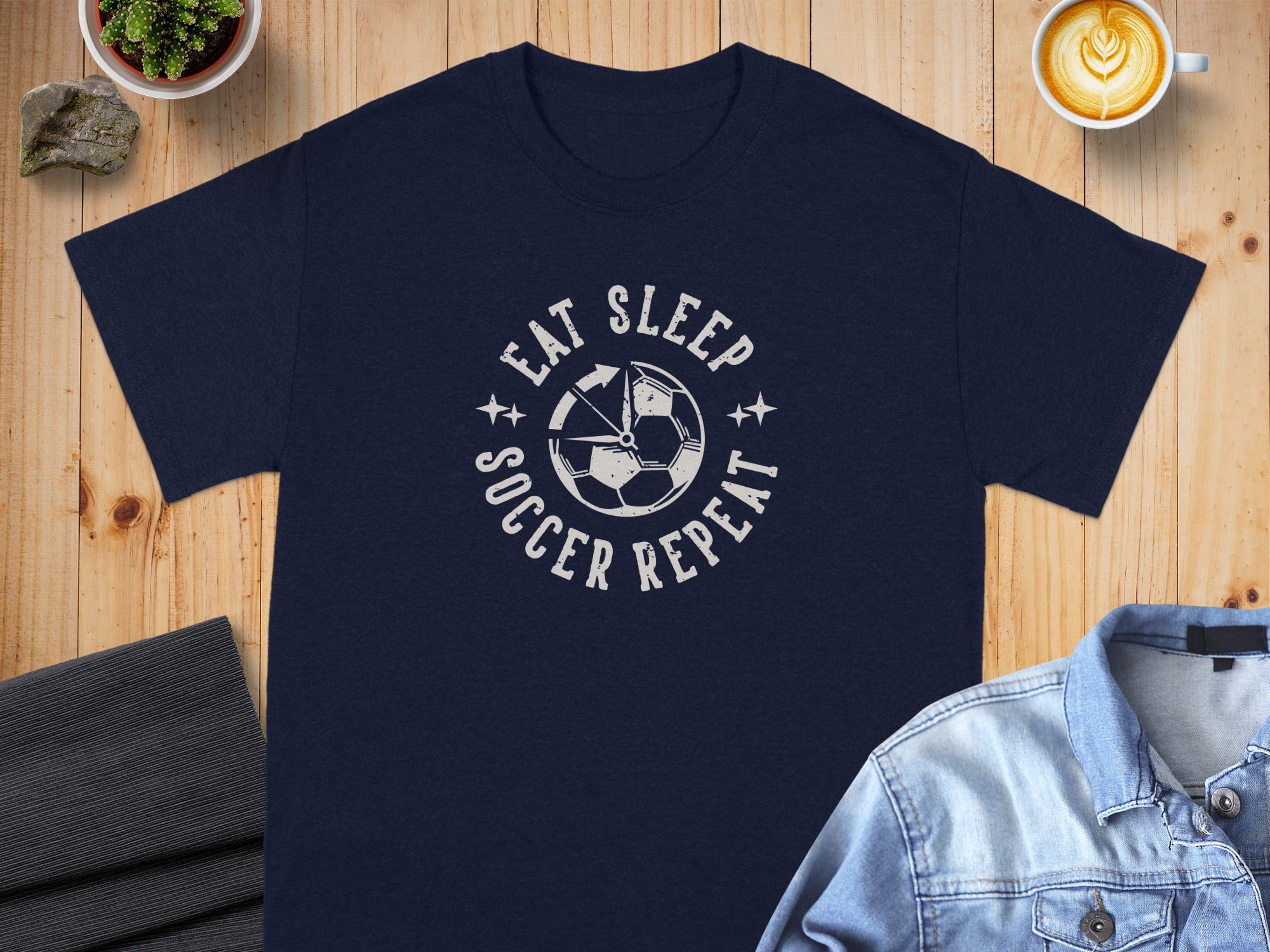 Navy t-shirt with a white "Eat Sleep Soccer Repeat" graphic and soccer ball.
