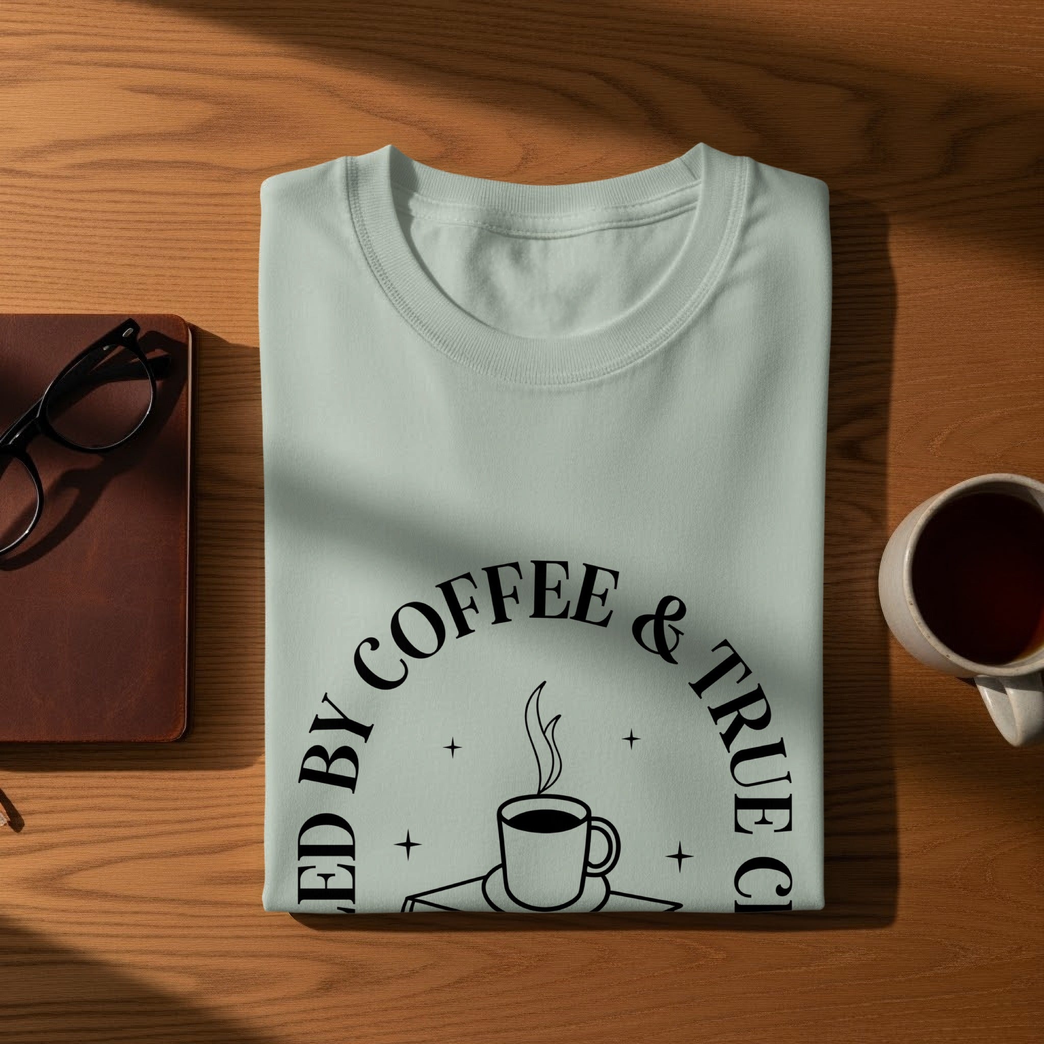 Light teal t-shirt with "Fueled by Coffee & True Crime" text and coffee cup graphic.