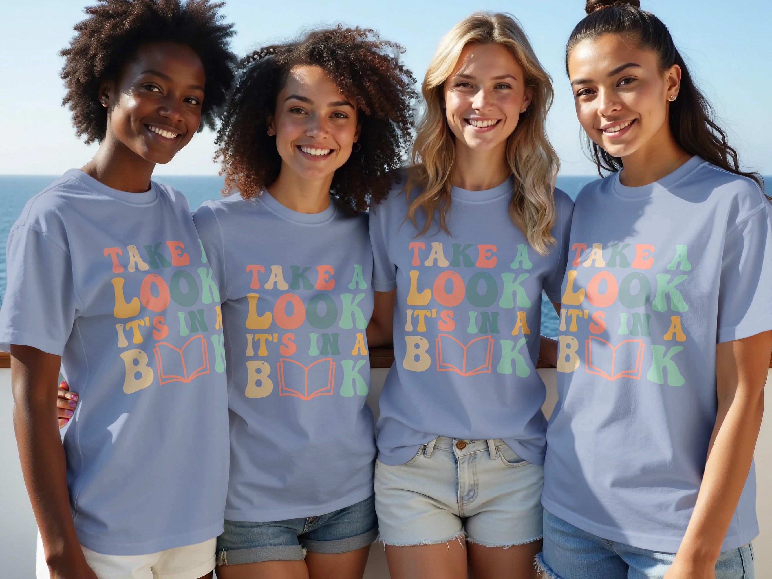 Four women wear light blue t-shirts with "TAKE A LOOK IT'S IN A BOOK" text.