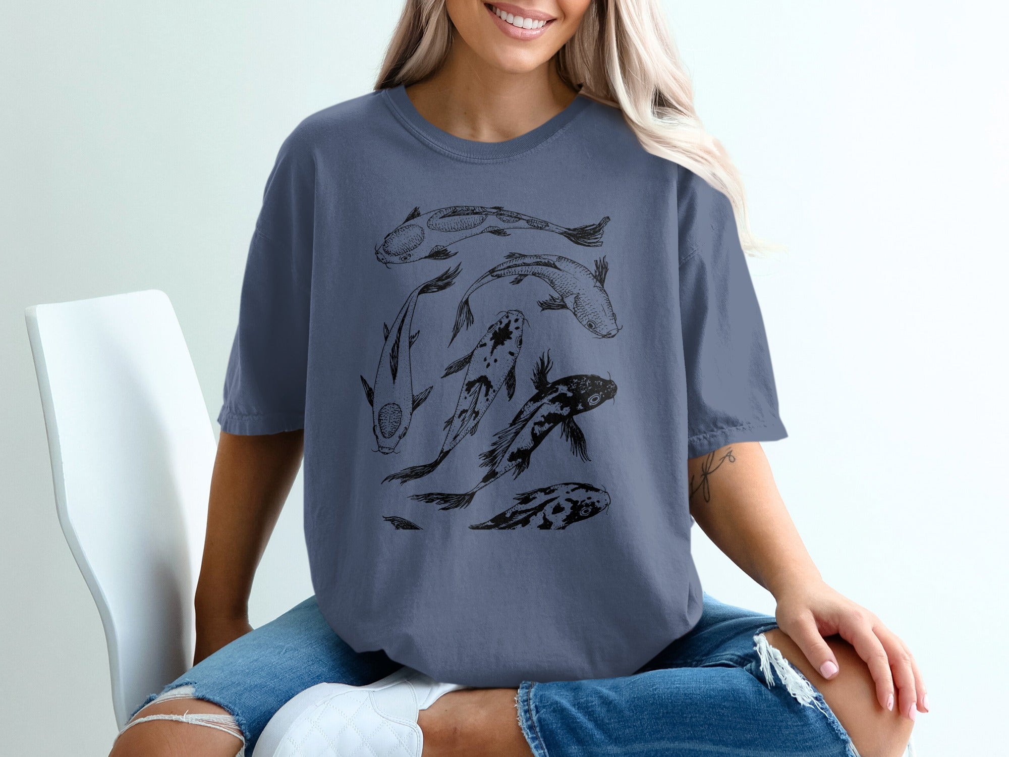 Blue t-shirt printed with a black sketch of several koi fish swimming.
