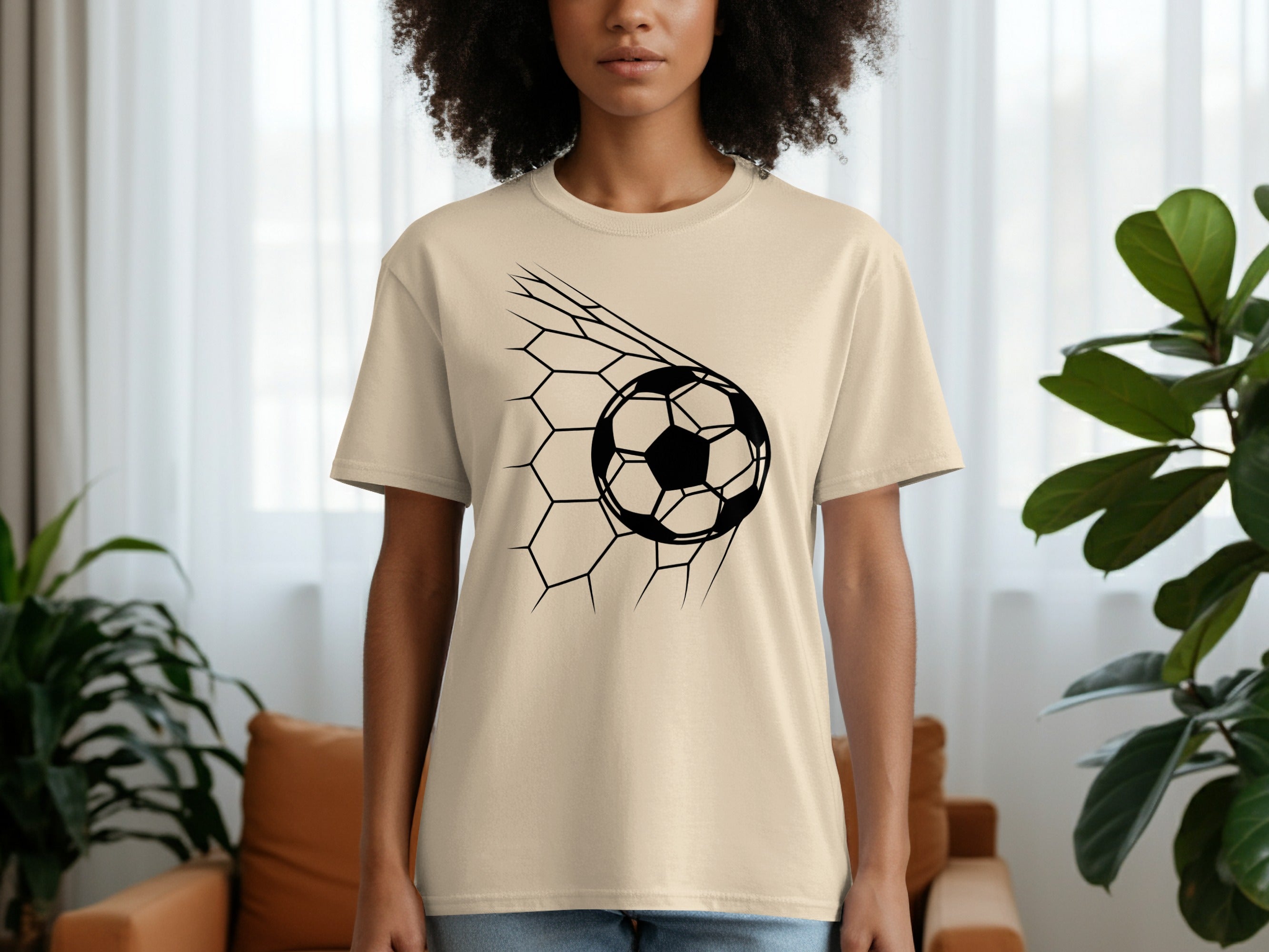 Cream t-shirt with a black graphic of a soccer ball breaking through a hexagonal net.