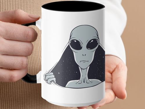 White mug with black interior featuring a gray alien peeking through a starry space background.