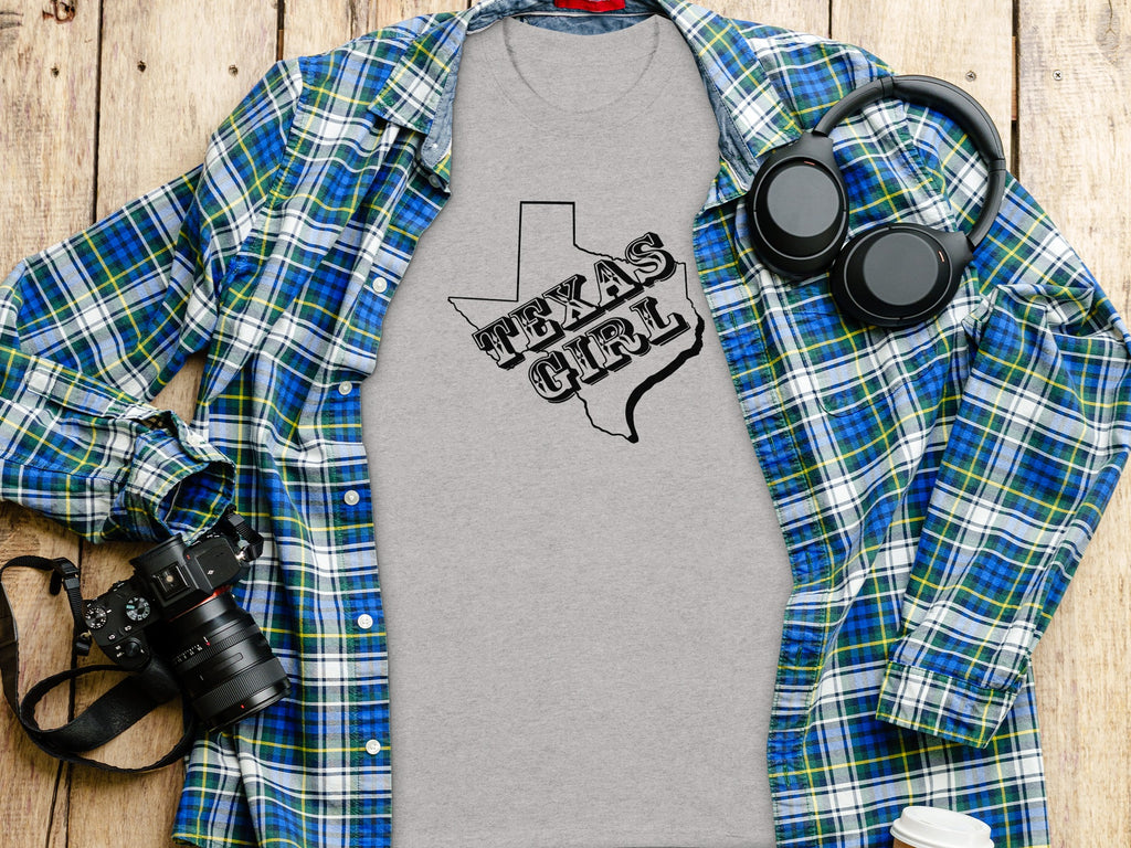 Grey t-shirt with black Texas outline and "Texas Girl" text, layered with plaid shirt.