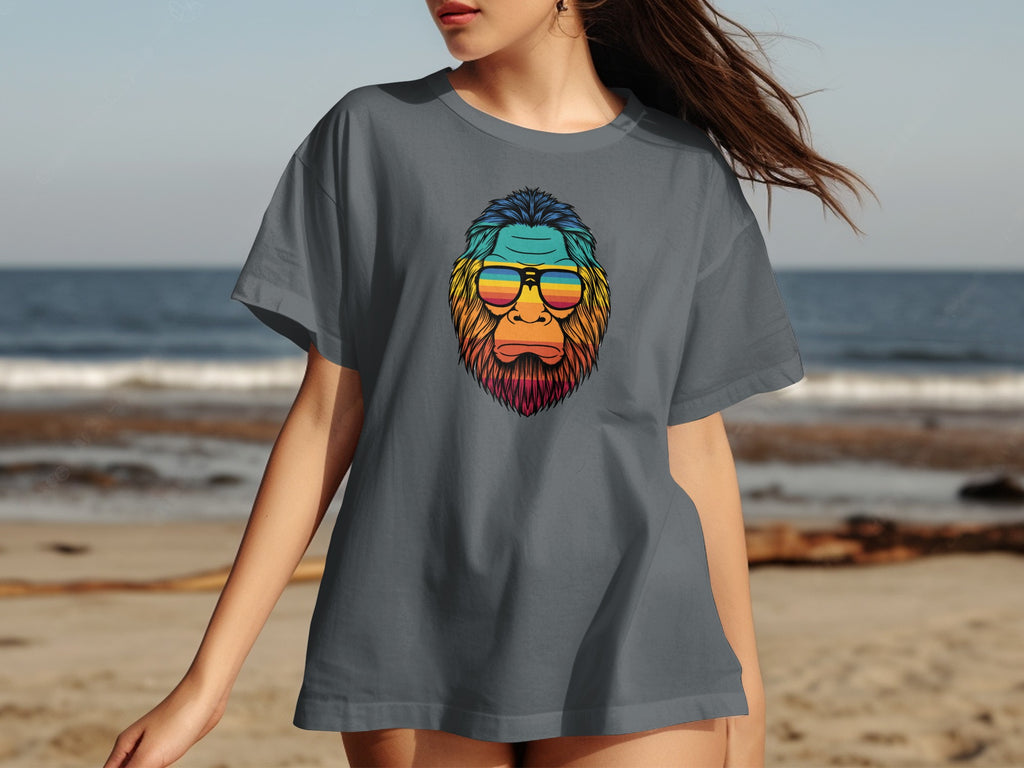Grey t-shirt with a colorful Bigfoot wearing sunglasses graphic on a beach