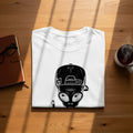 White t-shirt with a black alien wearing a backward baseball cap graphic.