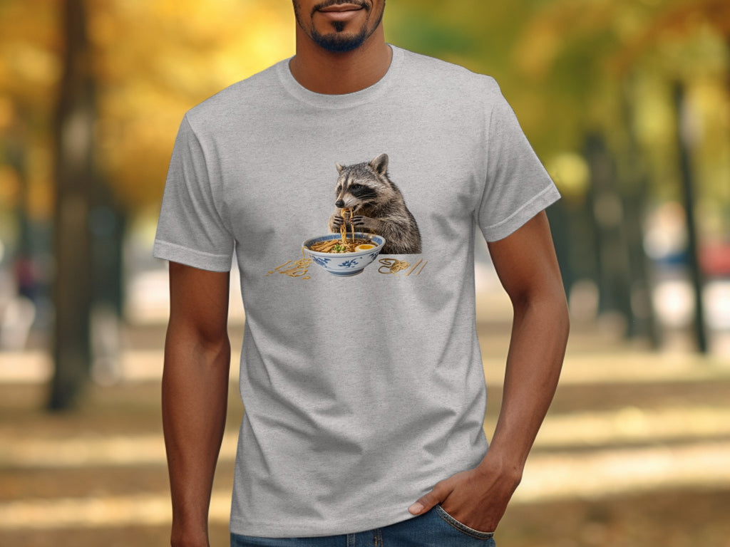 T-shirt graphic of a raccoon eating ramen noodles from a bowl with chopsticks.