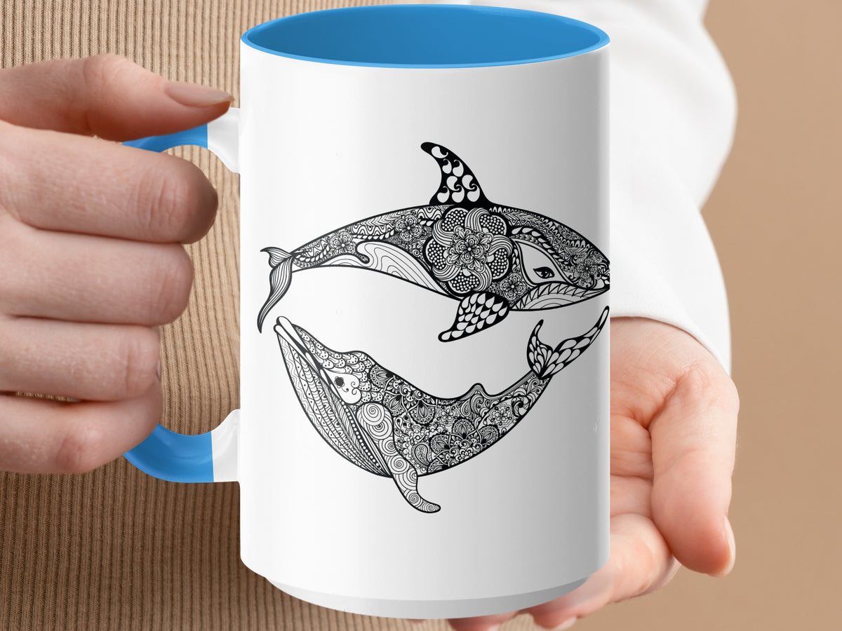 White mug with blue handle featuring decorative orca and whale designs.