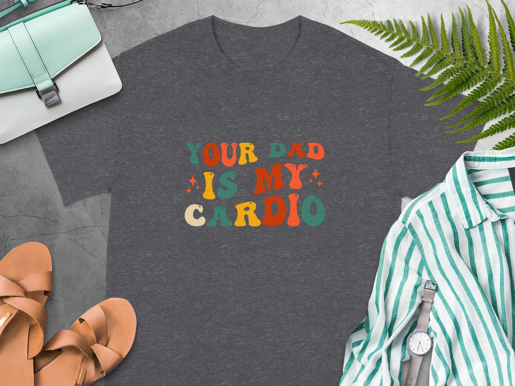 Dark gray t-shirt with colorful retro text reading "YOUR DAD IS MY CARDIO".