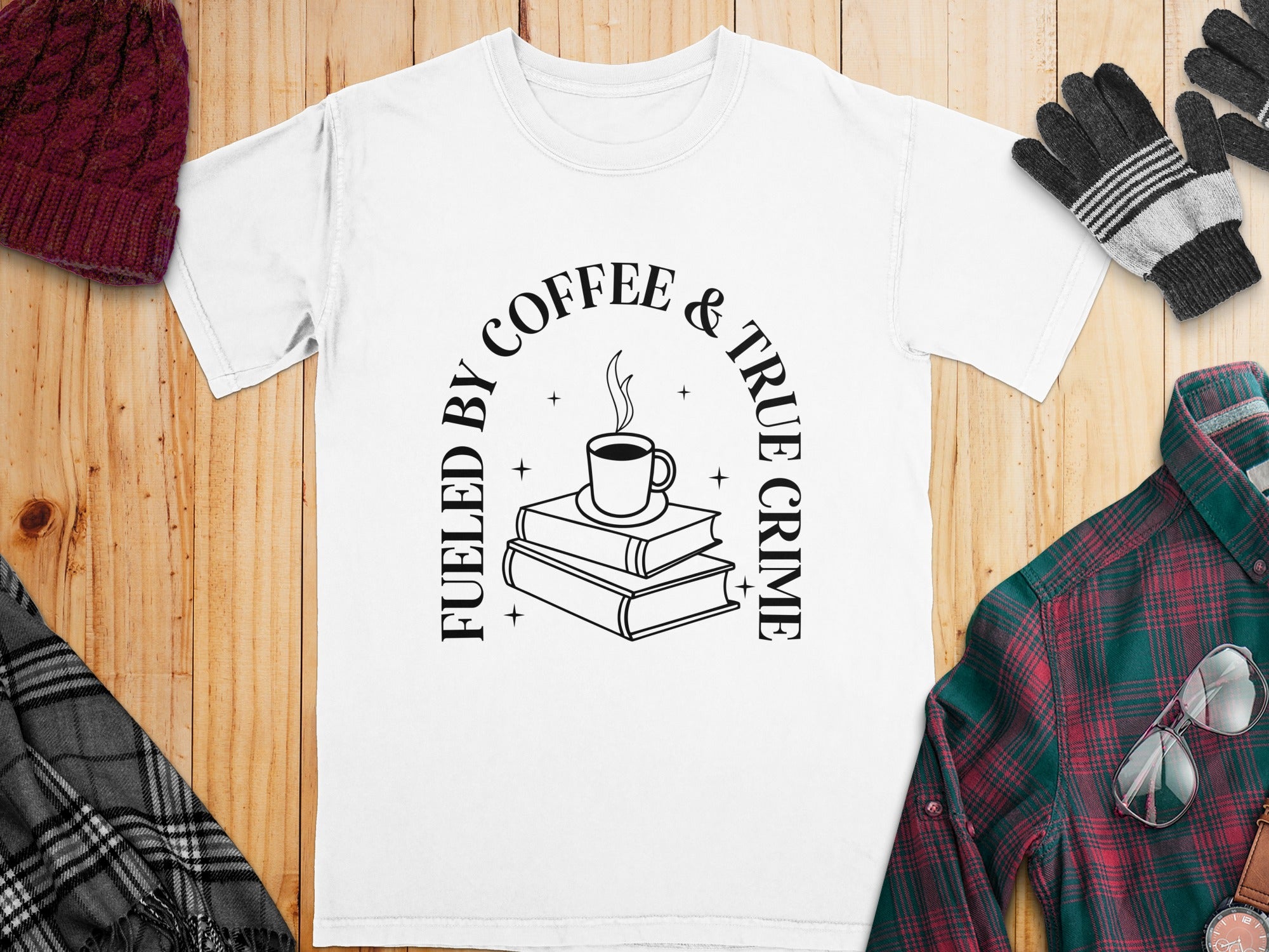 White t-shirt with "Fueled by Coffee & True Crime" text and coffee cup over books graphic.