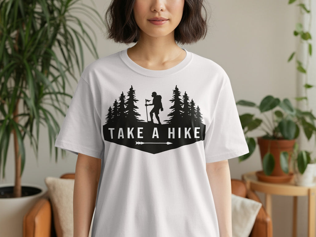 White t-shirt with black graphic featuring a hiker and trees, reading "TAKE A HIKE".