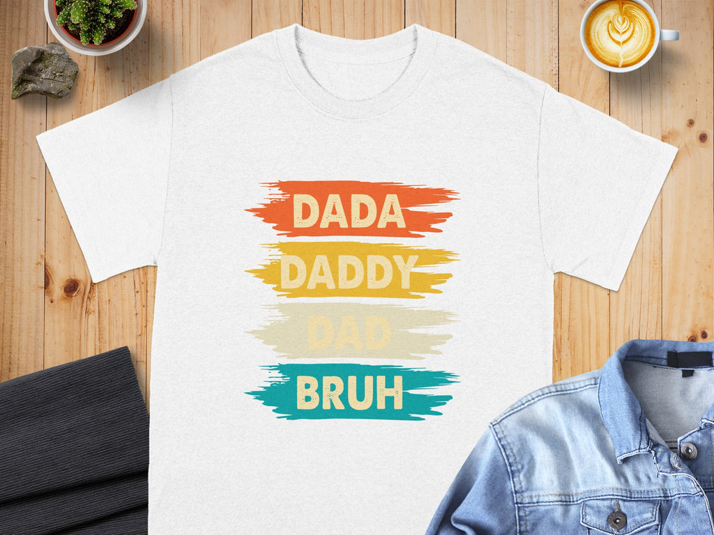 White t-shirt with text "DADA DADDY DAD BRUH" in distressed colorful stripes.