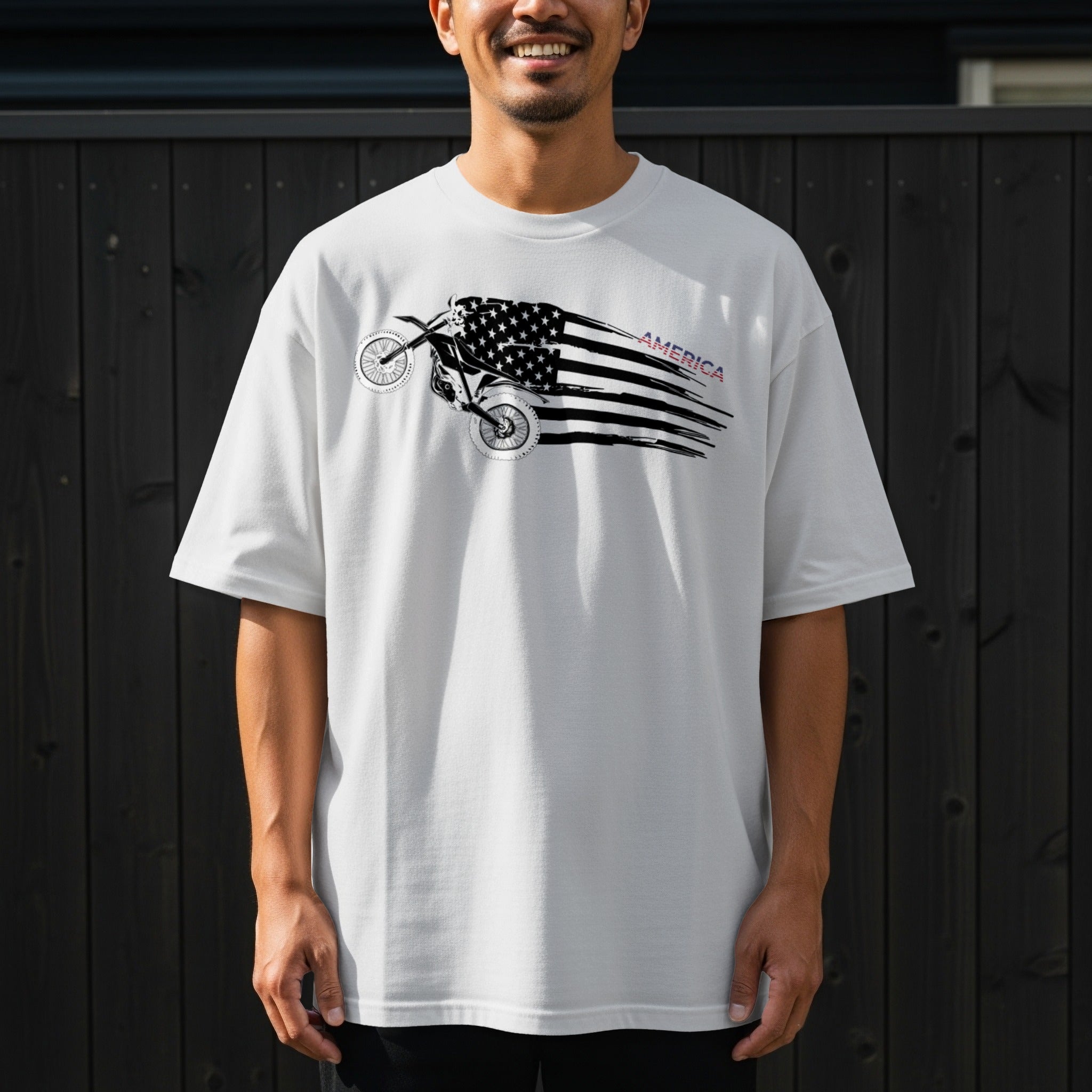 White t-shirt with a dirt bike graphic overlaid with an American flag and the word "AMERICA".