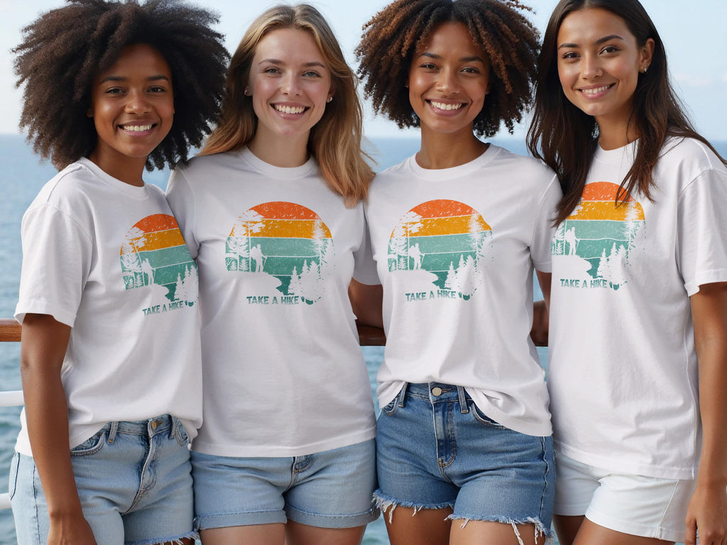 Four smiling women wear white t-shirts with a vintage sunset hike graphic.