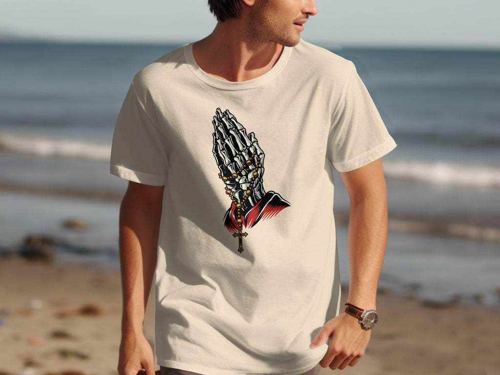 Skeleton praying hands with rosary and cross graphic on cream t-shirt.