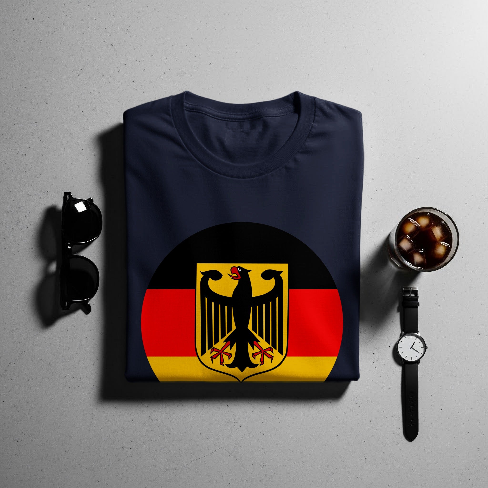 Navy t-shirt with German flag emblem, sunglasses, watch, and drink.