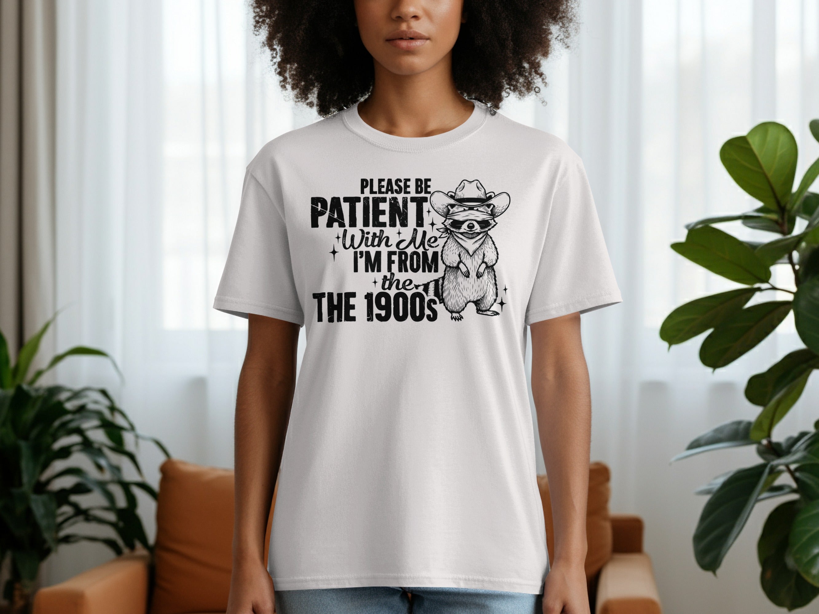 White t-shirt with raccoon wearing a cowboy hat and sunglasses; text "Please be patient with me I'm from the 1900s".