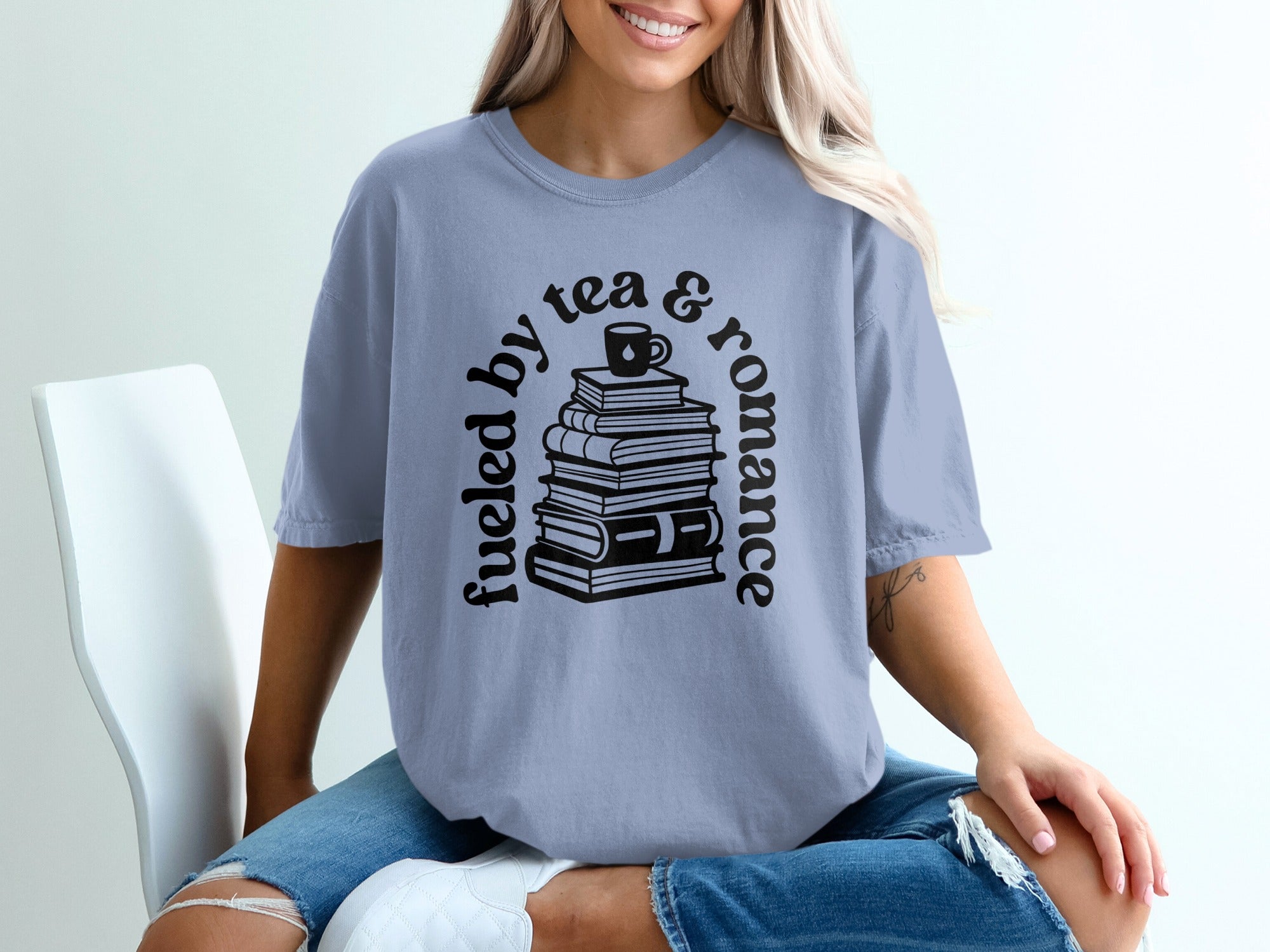Crewneck t-shirt with stacked books and text "Fueled by tea & romance"