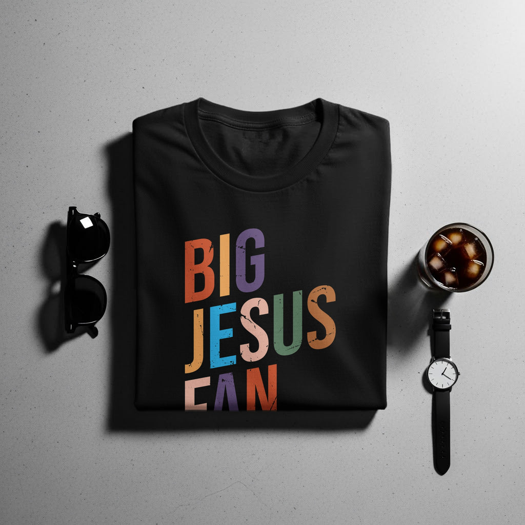 Black t-shirt with colorful "BIG JESUSCAN" text and sunglasses, watch, and drink.