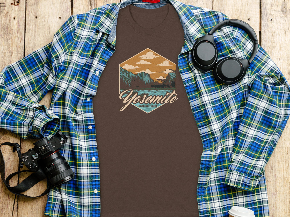 Brown t-shirt with Yosemite National Park graphic, open plaid shirt, headphones, and camera.