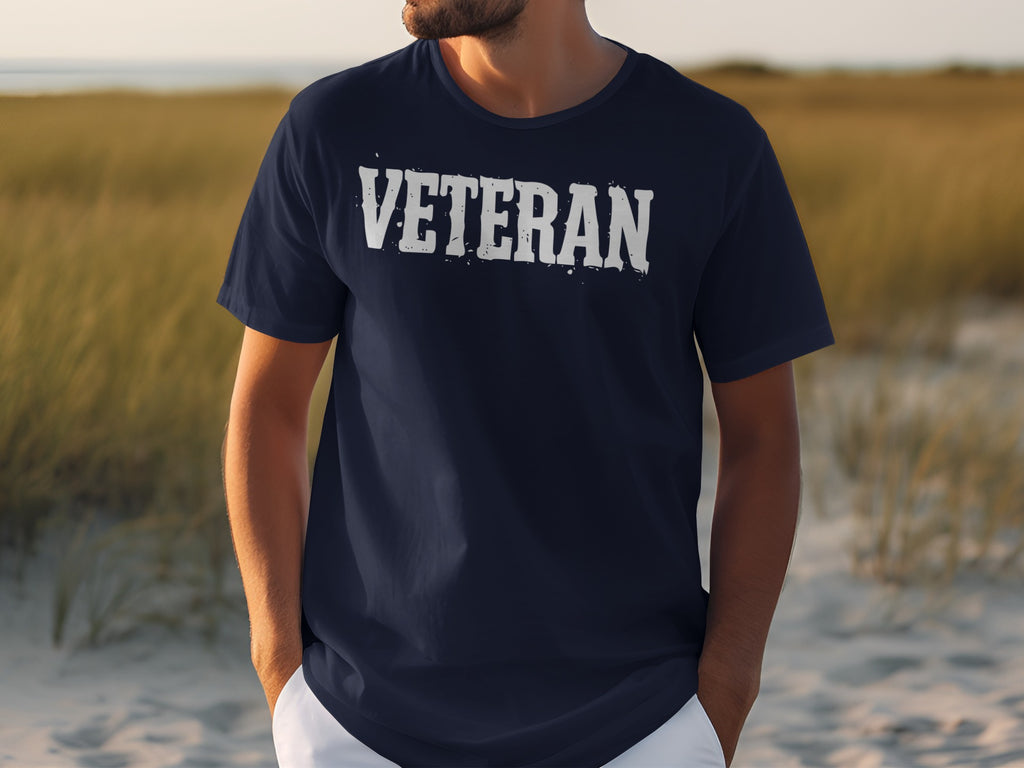 Navy t-shirt with white distressed "VETERAN" text on chest, man standing outdoors.