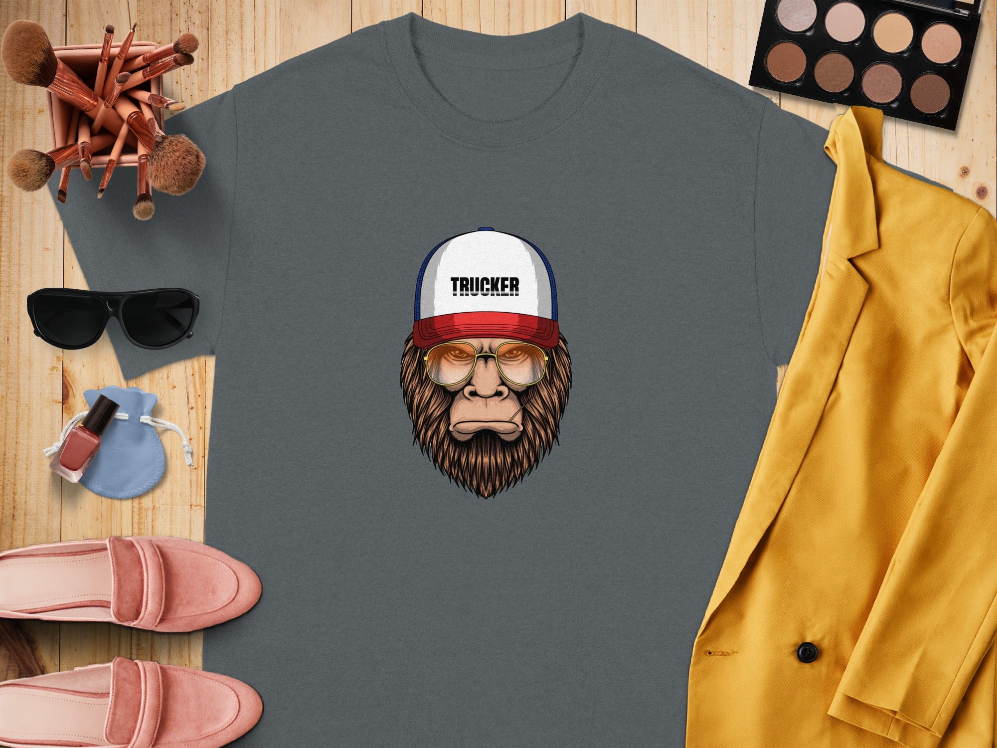 T-shirt with Bigfoot wearing a trucker hat and glasses; flat lay.